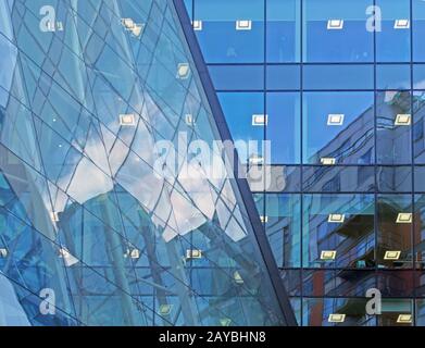 il cielo blu e gli edifici si riflettono e si specchiano in un grande e moderno edificio di uffici commerciali futuristici Foto Stock