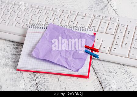 Quaderno di carta quadrato con una nota vuota a forma di rettangolo sopra fissata da due zoccoli sul foglio. Tastiera bianca sotto una c Foto Stock