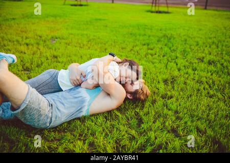 Il tema è lo sport e uno stile di vita sano. Una giovane coppia di uomini e donne riposano distesi sulle loro spalle sull'erba verde, un prato Foto Stock