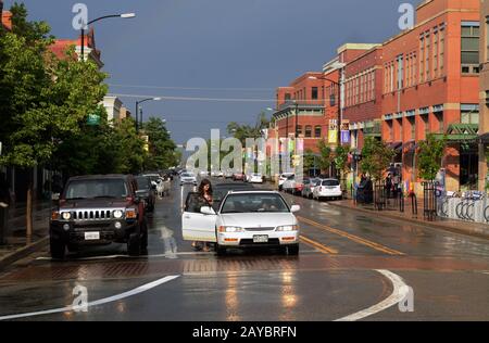 Una donna entra in una macchina fermata a Pearl St. E 15th St. Nella città di Boulder Colorado dopo una pioggia estiva. Foto Stock