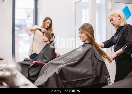 bella donna pettinatura capelli bagnati. stilista spazzolatura capelli donna in salone. Parrucchiere Al Servizio Del Cliente. Professionista Giovane Hairdre Foto Stock