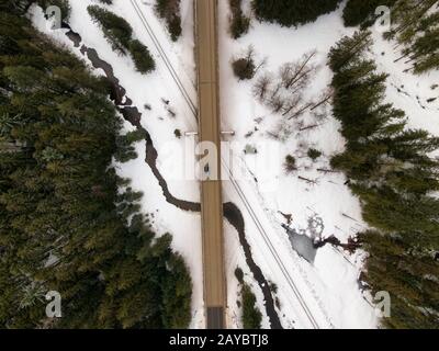 Veduta aerea Dall'Alto di un'autostrada che attraversa il fiume e i binari ferroviari durante l'inverno. Preso nell'interno della Columbia Britannica, Canada. Foto Stock