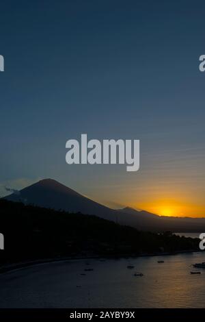 Vista del Monte Agung (un vulcano attivo) dal punto di tramonto Amed al tramonto a Bali Est, Indonesia. Foto Stock