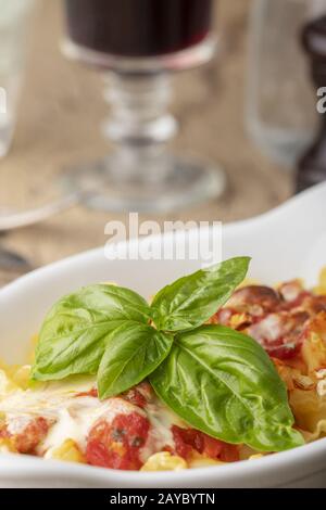 Pasta gratinata su legno con vino Foto Stock