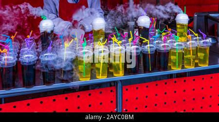 Fila di frutta colorata bevande analcoliche in tazzine di plastica con fumo bianco Foto Stock