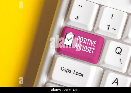 Scrittura a mano testo scrittura mentalità positiva. Concetto che significa atteggiamento mentale in cui ci si aspetta risultati favorevoli White pc keyboar Foto Stock