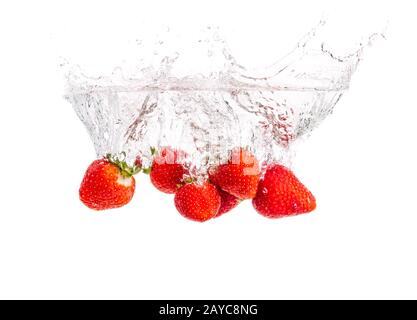 Le fragole di cadere in acqua causando bolle tutto intorno. Cibo sano concetto Foto Stock