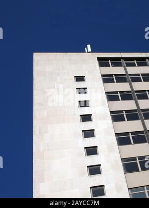 vista prospettica d'angolo di un vecchio edificio bianco in cemento degli anni '60 contro un cielo blu Foto Stock