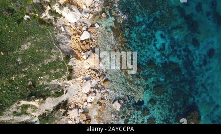 Veduta aerea della costa rocciosa del mare e della spiaggia di San Blas Bay a Gozo, l'isola più piccola di Malta Foto Stock