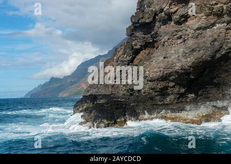 Il surf sta rompendo sulla costa di Na Pali sul lato occidentale dell'Isola Hawaiiana di Kauai, Hawaii, Stati Uniti. Foto Stock