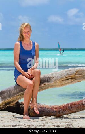 Donna olandese siede sul tronco dell'albero alla spiaggia Foto Stock