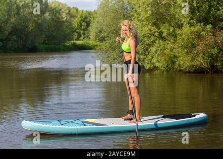 Donna caucasica in piedi pagaia con SUP Foto Stock