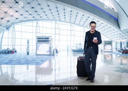 Uomo su smart phone - young business man in aeroporto. Casual urbano imprenditore professionale utilizza lo smartphone sorridendo felice all'interno Foto Stock