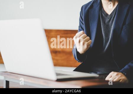 Un uomo d'affari di successo eccitato pugno clenched davanti al calcolatore Foto Stock