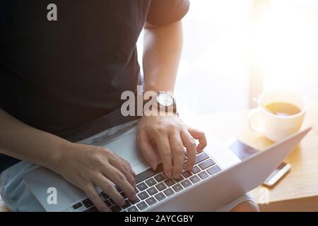 Laptop in mano imprenditore con lo smartphone e caffè . Foto Stock