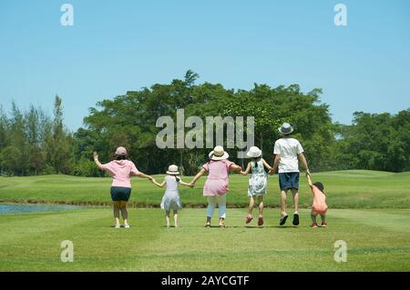 Famiglia jumping insieme mano nella mano godere nel parco Foto Stock