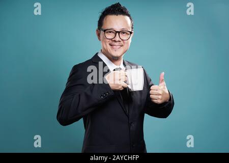 Imprenditore nel soddisfare il sorriso e gustatevi una tazza di caffè con il pollice fino gesto. Foto Stock