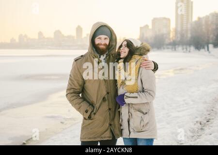 Tema amore e data sulla natura. Un giovane ragazzo e una ragazza della coppia eterosessuale caucasica camminano in inverno lungo un lago ghiacciato in wint Foto Stock