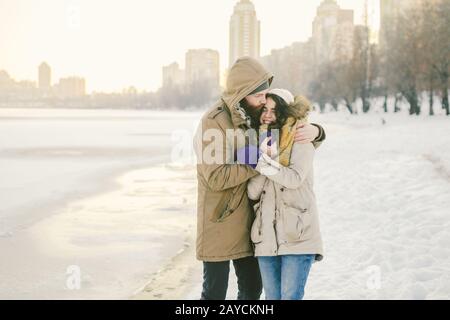 Tema amore e data sulla natura. Un giovane ragazzo e una ragazza della coppia eterosessuale caucasica camminano in inverno lungo un lago ghiacciato in wint Foto Stock