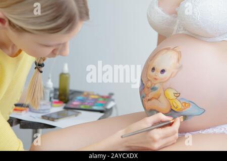 L'artista di trucco disegna un bambino sulla pancia Foto Stock