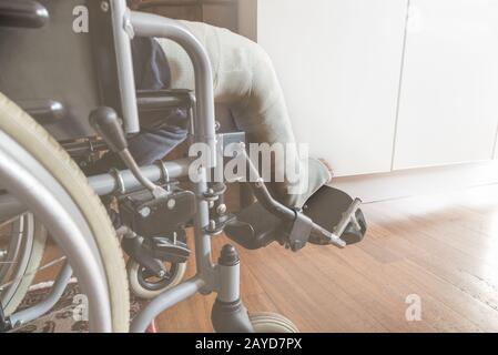 Gamba in gesso di un bambino su una sedia a rotelle. Concetto di salute, incidente, medico. Messa a fuoco selettiva sul piede, vista laterale. Persona irriconoscibile Foto Stock