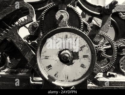 antico orologio in ferro rotto arrugginito con faccia intemperata e meccanismo complesso esposto di denti e ingranaggi Foto Stock