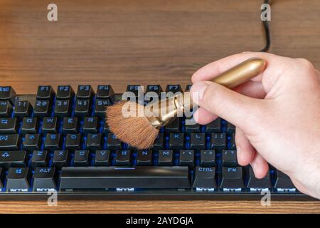 la mano maschio pulisce la tastiera da polvere e sporcizia Foto Stock