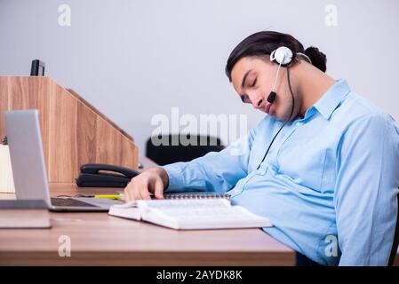 Operatore di call center al lavoro presso la sua scrivania Foto Stock
