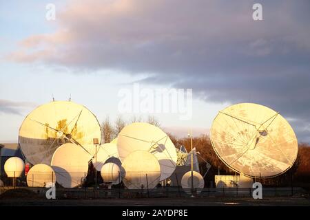 Antenna e antenna parabolica di grandi dimensioni per comunicazioni e reti di tecnologia mobile al tramonto con luce brillante Foto Stock