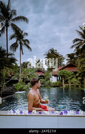 Guy bere cocktail in piscina durante la vacanza in Thailandia Foto Stock