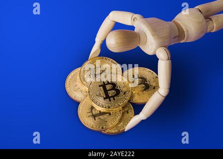 Personaggio giocattolo in legno con bitcoins su blu Foto Stock