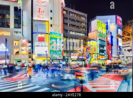 Shibuya, TOKYO, GIAPPONE - 29 dicembre 2019: Famosa stazione di Shibuya e attraversamento di strada nella città di Tokyo di notte con gente offuscata e bolletta luminosa Foto Stock