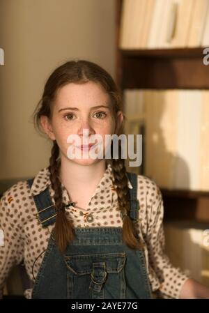 Una giovane ragazza carina sorridente, con occhi verdi, capelli rossi, frane e pigtail. Foto Stock