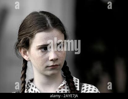 Una giovane ragazza carina con i temerari e i pigtail. Foto Stock