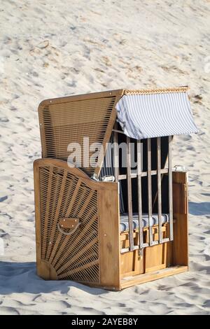 Una sedia da spiaggia chiusa si trova solo sulla spiaggia del Mar Baltico Foto Stock