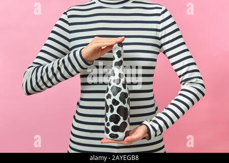 La ragazza vestita con camicia a righe contiene una bottiglia di vino dipinta. Foto Stock