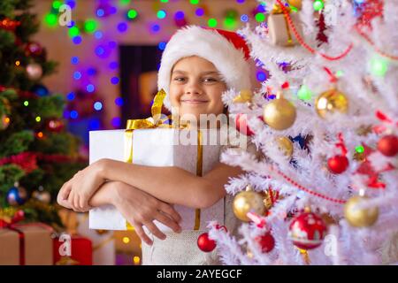 La ragazza in albero di Natale detiene un grande dono nelle sue mani Foto Stock