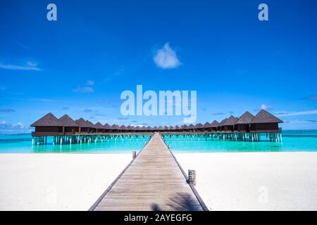 I bungalow sull'acqua e pontile in legno alle Maldive Foto Stock