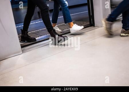 Motion passeggeri sfocati che entrano alla porta del carro in una stazione della metropolitana di Brescia (Lombardia, Italia). Pavimentazione tattile per guidare le persone cieche. Foto Stock