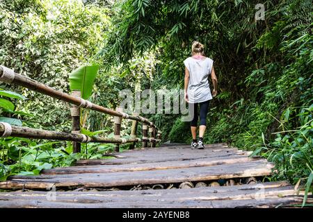Ragazza in tights camminare su un vecchio ponte di legno nel mezzo della foresta nel nord della thailandia Foto Stock