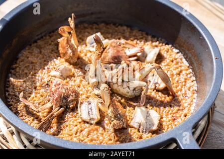 Riso con frutti di mare servito in una pentola di ferro in un tavolo di legno in una terrazza di un ristorante all'aperto Foto Stock