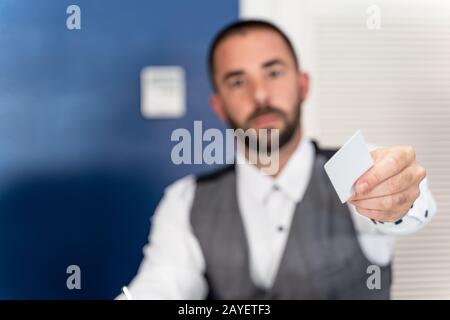 Foto di scorta di una mano che dà una scheda della camera da un receptionist sfocato sullo sfondo Foto Stock