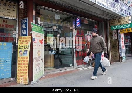 Un uomo, presumibilmente asiatico americano, negozi sulla Main Street a Chinatown in una giornata invernale frigid. A Flushing, New York City Foto Stock
