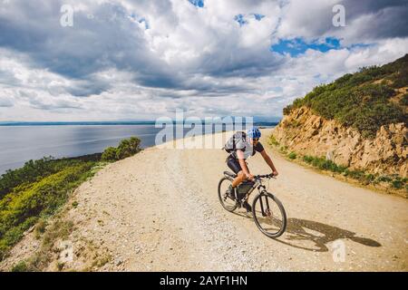 Un giovane ragazzo che guida una mountain bike su un percorso in bicicletta in Spagna. L'atleta in mountain bike corre fuori strada sullo sfondo o Foto Stock