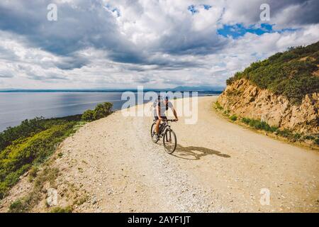 Un giovane ragazzo che guida una mountain bike su un percorso in bicicletta in Spagna. L'atleta in mountain bike corre fuori strada sullo sfondo o Foto Stock