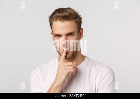 Primo piano pensoso e intelligente buon-look giovane uomo concentrato, toccare il labbro e squinting ponderare, ascoltare interessante concerto o sug Foto Stock