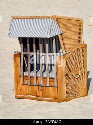 Una sedia da spiaggia chiusa si trova solo sulla spiaggia del Mar Baltico Foto Stock