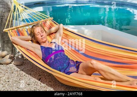 Donna olandese che si rilassa in amaca vicino alla piscina Foto Stock