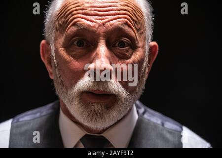 Ritratto di uomo anziano sorpreso su sfondo nero. Foto Stock