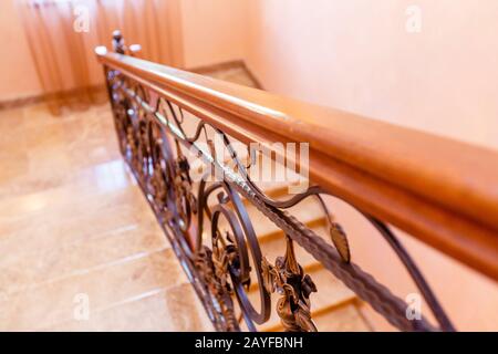 scala in ferro battuto nel cottage. Gradini in marmo, scale in ferro battuto nero con ornamenti floreali. Ringhiera in legno di mogano. La scala tra f Foto Stock